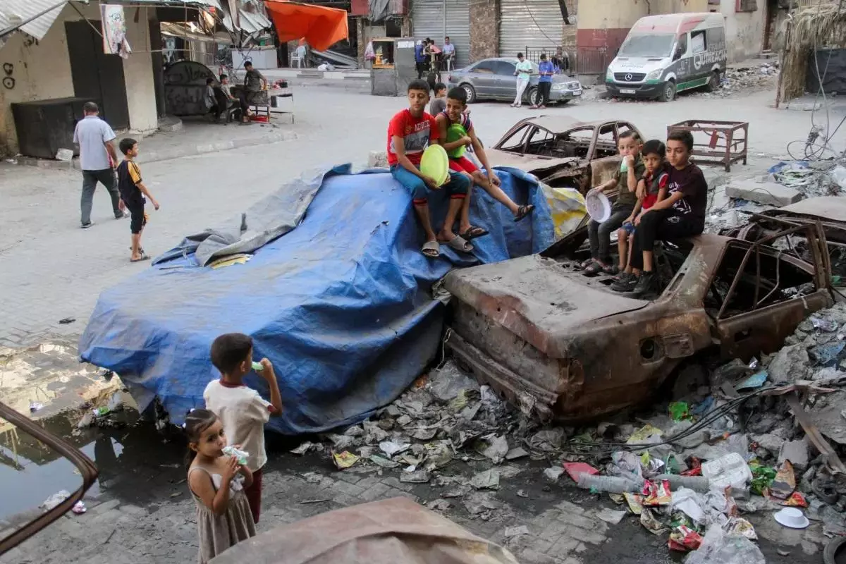 Children sit on damaged cars as conflict between Israel and Hamas continues, in the northern Gaza Strip on August 14.