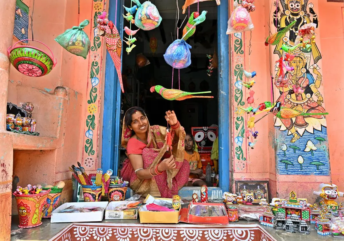 A woman displays toys outside her house at Raghurajpur heritage village, known for Pattachitra and palm leaf engravings, in Puri on April 1, 2025. Today, handcrafted objects circulate as markers of taste and distinction, even as the caste-based labour that produces them remains undervalued and precarious.