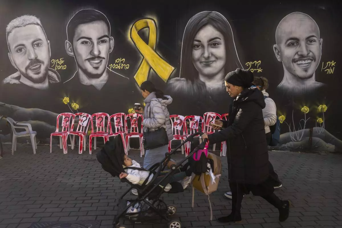 An ultra-Orthodox Jewish woman walks past an installation, and a mural of portraits of hostages held by Hamas, in Gaza, in Jerusalem on January 21, 2025.