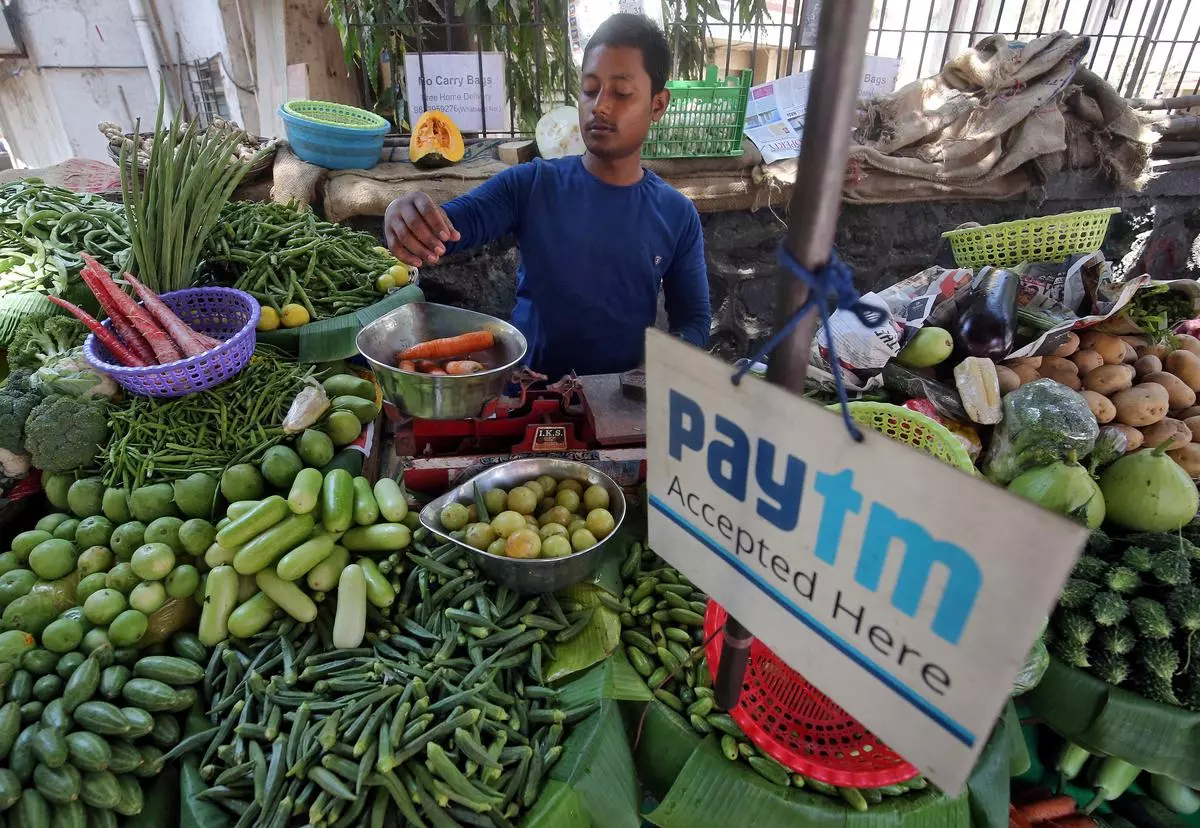 A vendor weighs vegetables next to a Paytm advertisement at a roadside market in Mumbai.