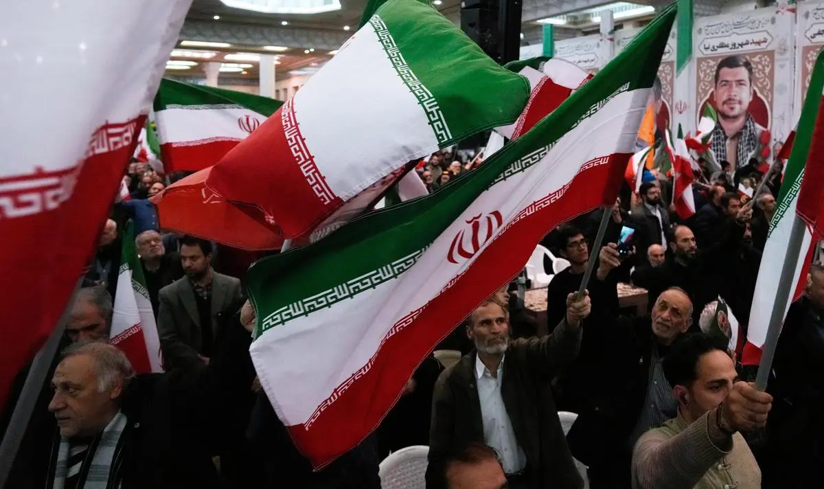 People wave national flags during the commemoration of the death anniversary of the commander of Iran’s Revolutionary Guard expeditionary Quds Force, General Qasem Soleimani, who was killed in a US drone attack in 2020, in Tehran on January 1, 2026.