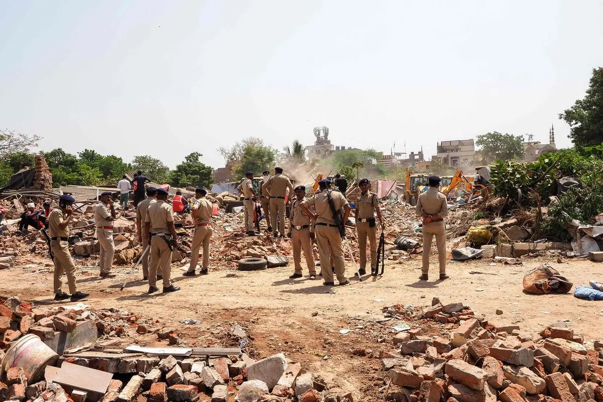 Police stand guard as bulldozers are used to raze a settlement of alleged illegal immigrants from Bangladesh in Ahmedabad on April 29, 2025. The police detained over 1,000 “Bangladeshi migrants” in a sweeping crackdown in Gujarat with the aim of deporting people living there illegally, the State government said April 26. 