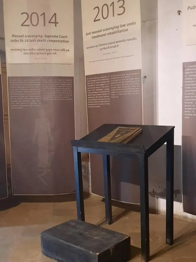 Exhibit name: Moral Compass. A copy of India’s constitution is placed in the middle of panels that displays human rights movements spanning several years. Exhibit name: Moral Compass. A copy of India’s constitution is placed in the middle of panels that displays human rights movements spanning several years.