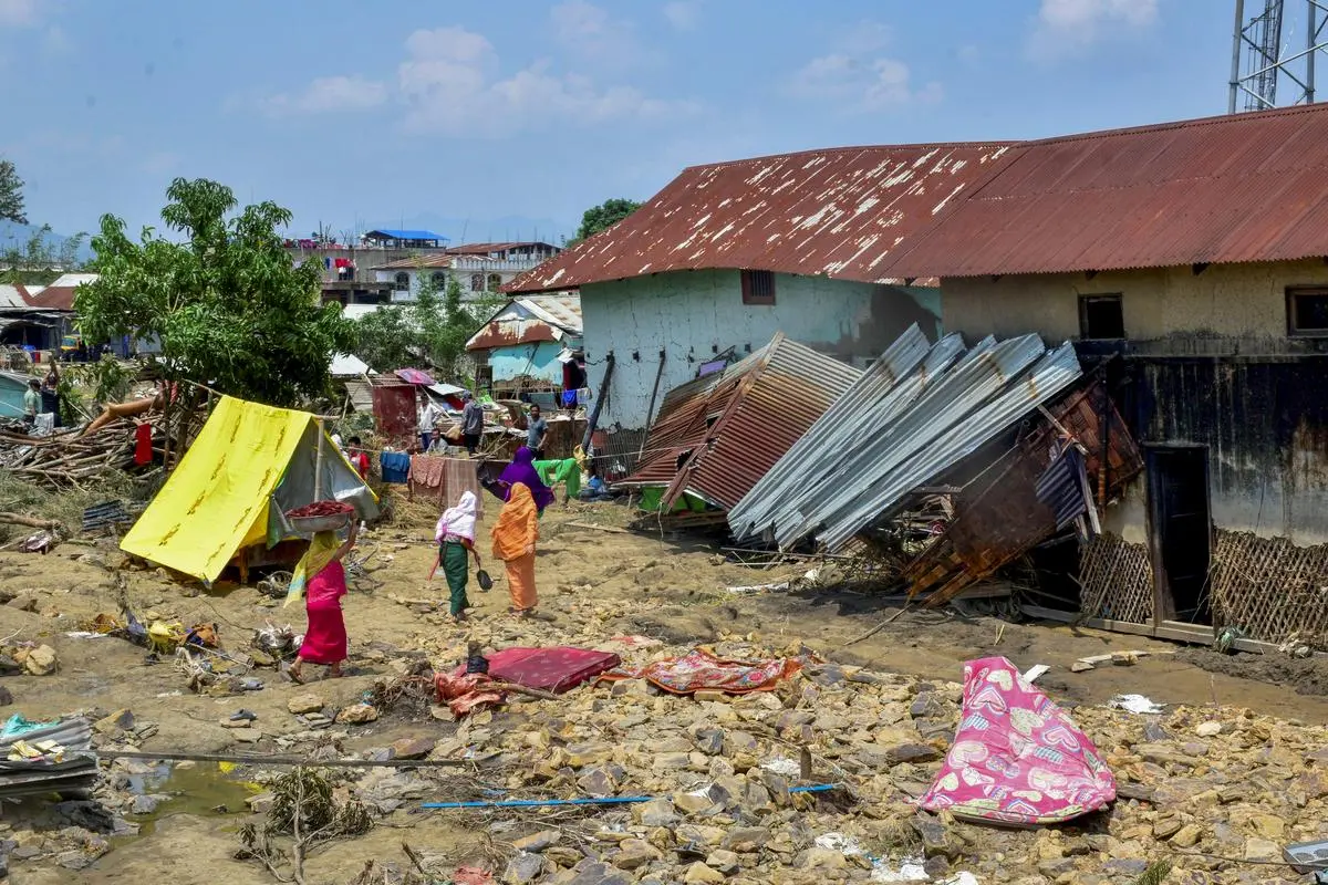 People walk past debris and damaged objects in the aftermath of the rain-triggered floods in the Khurai Heikrumakhong area of Imphal East district, Manipur, on June 5. People walk past debris and damaged objects in the aftermath of the rain-triggered floods in the Khurai Heikrumakhong area of Imphal East district, Manipur, on June 5.