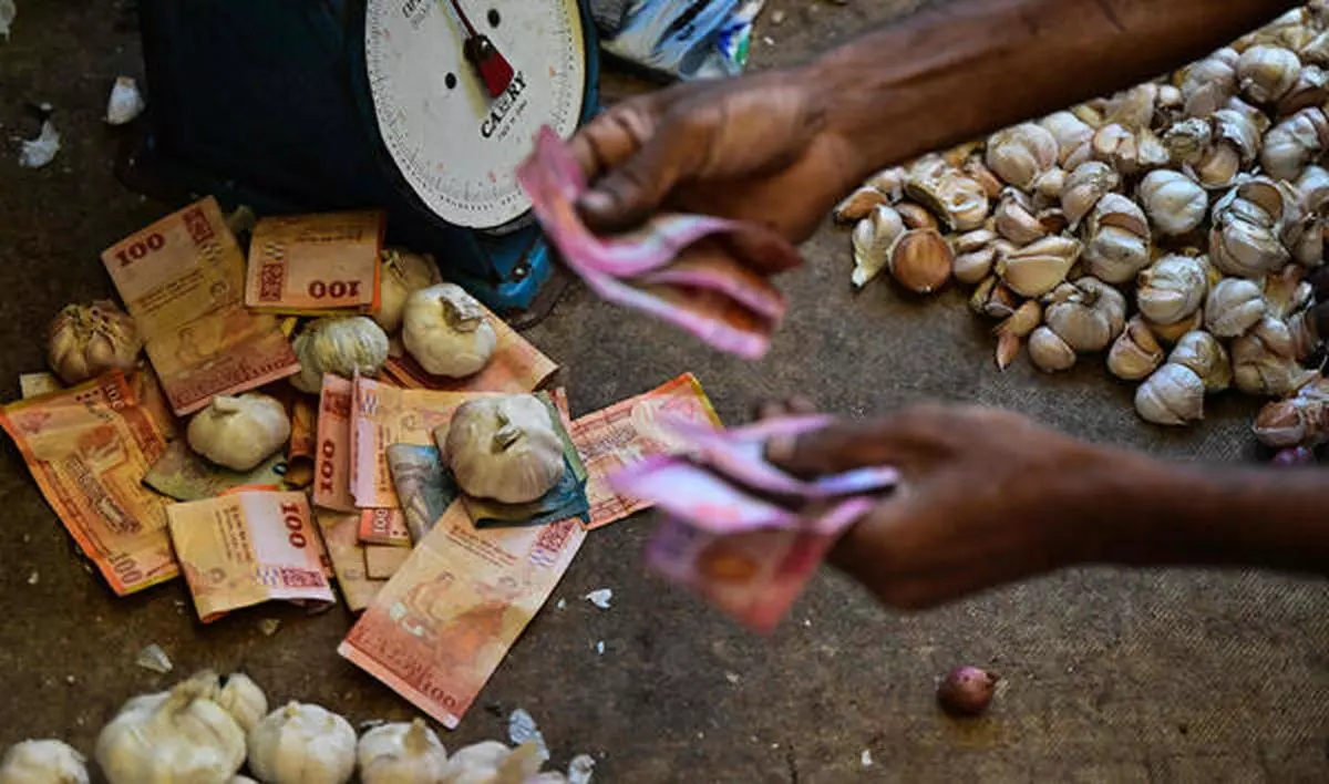 A vendor holds Sri Lankan bank notes while working at a market in Colombo on December 13, 2023. The International Monetary Fund revived its $2.9 billion bailout for Sri Lanka on December 12 after the South Asian nation clinched a debt restructuring deal with China, its biggest official lender. 