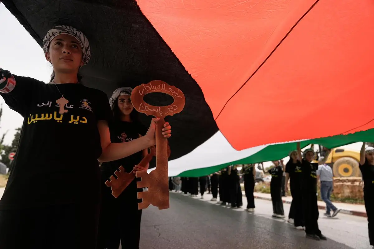 Students carrying a Palestinian flag and mock keys of the homes their families left behind (this one reads: 'Deir Yassin; I am going back'), at event commemorating the  Nakba Day, in Ramallah on May 12, 2026.