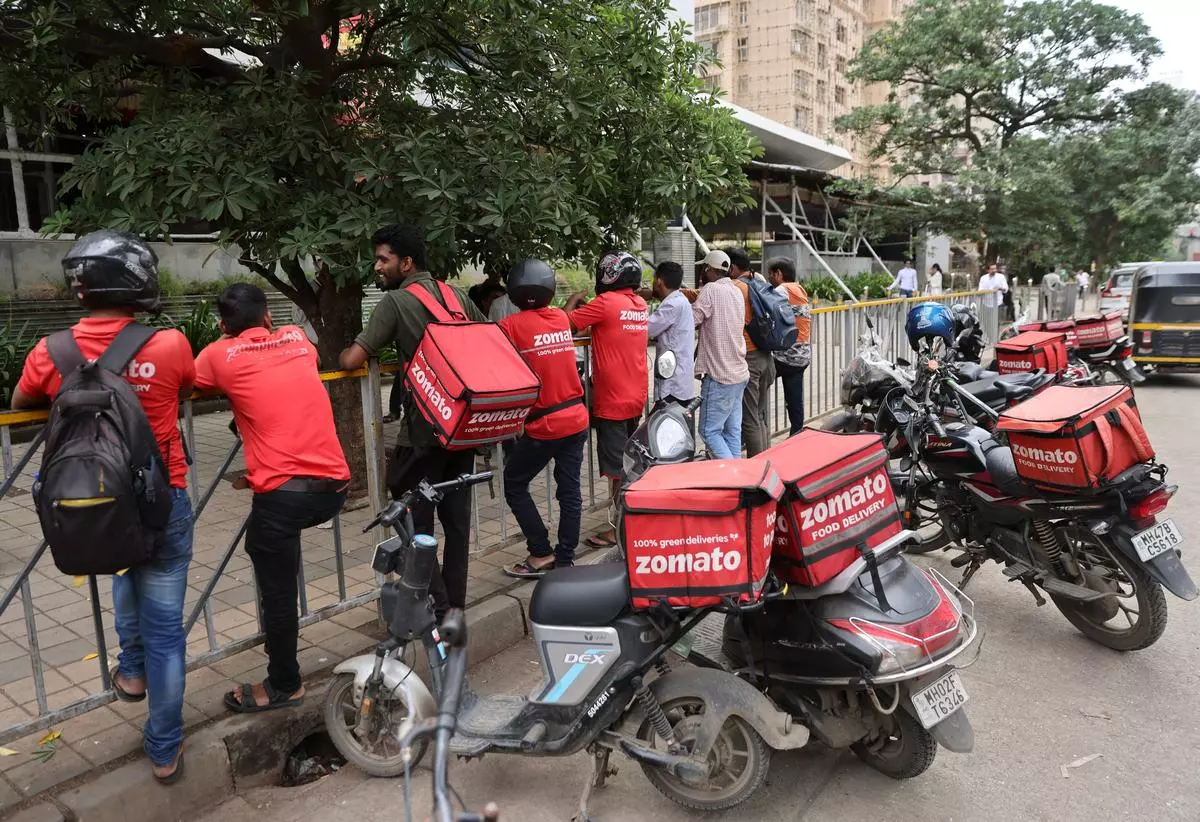 Gig workers are the bonded labourers of the digital age. Here, they wait to collect their orders outside a mall in Mumbai, in August 2023.