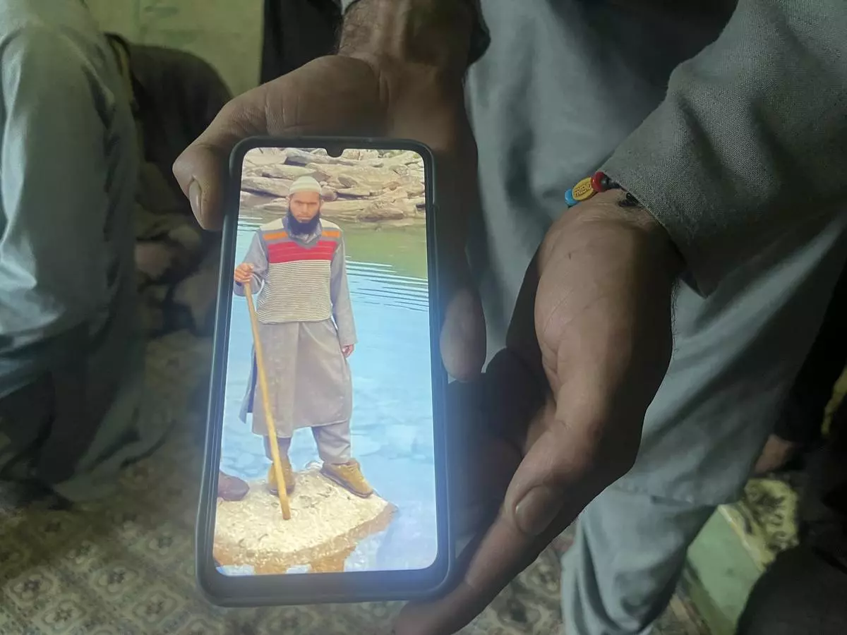 A family member shows a photo of 40-year-old Mehrajuddin.