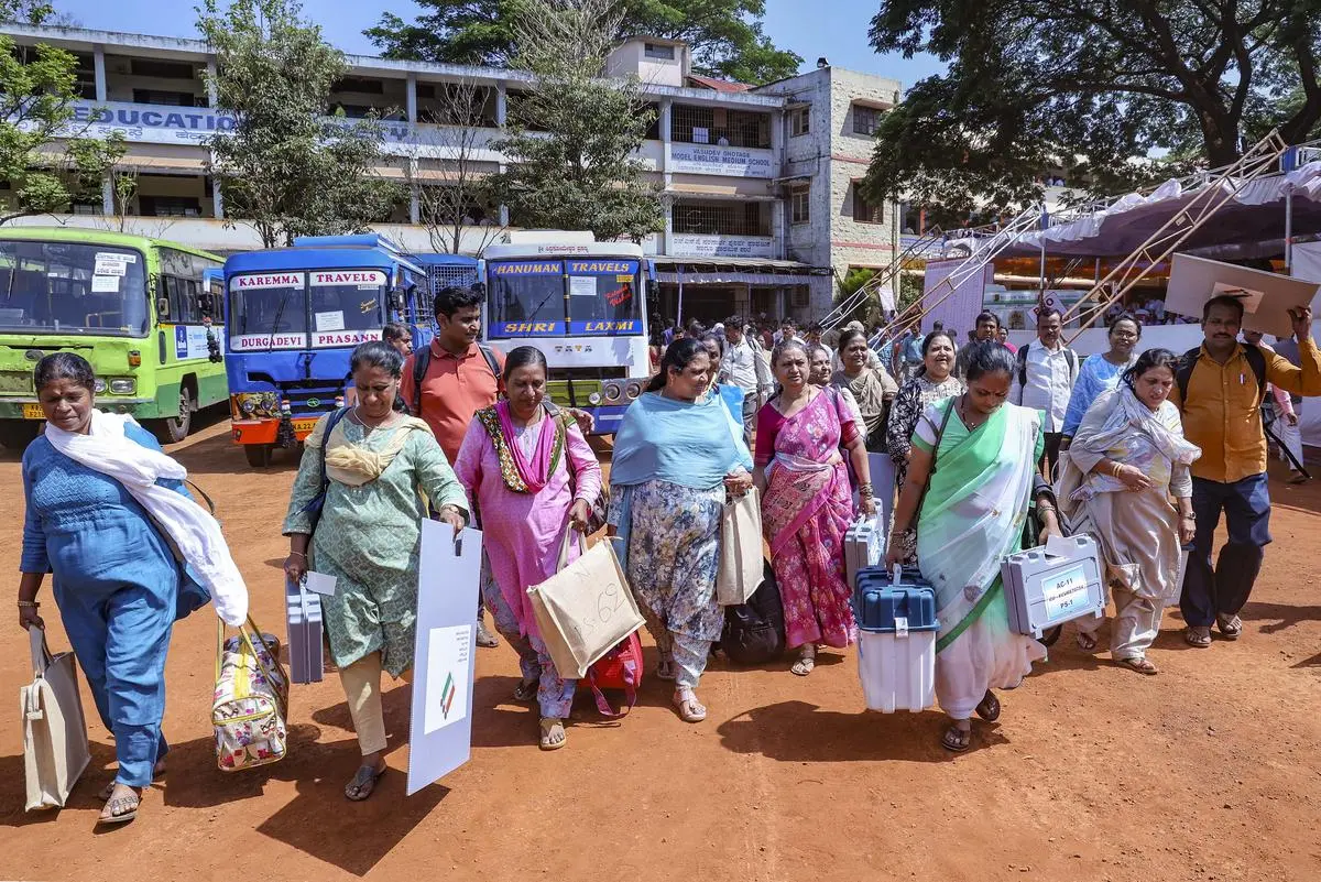 Polling officials walk to their respective polling booths, a day before the voting in the third phase of Lok Sabha election in Belagavi, Karnataka, on May 6, 2024. 