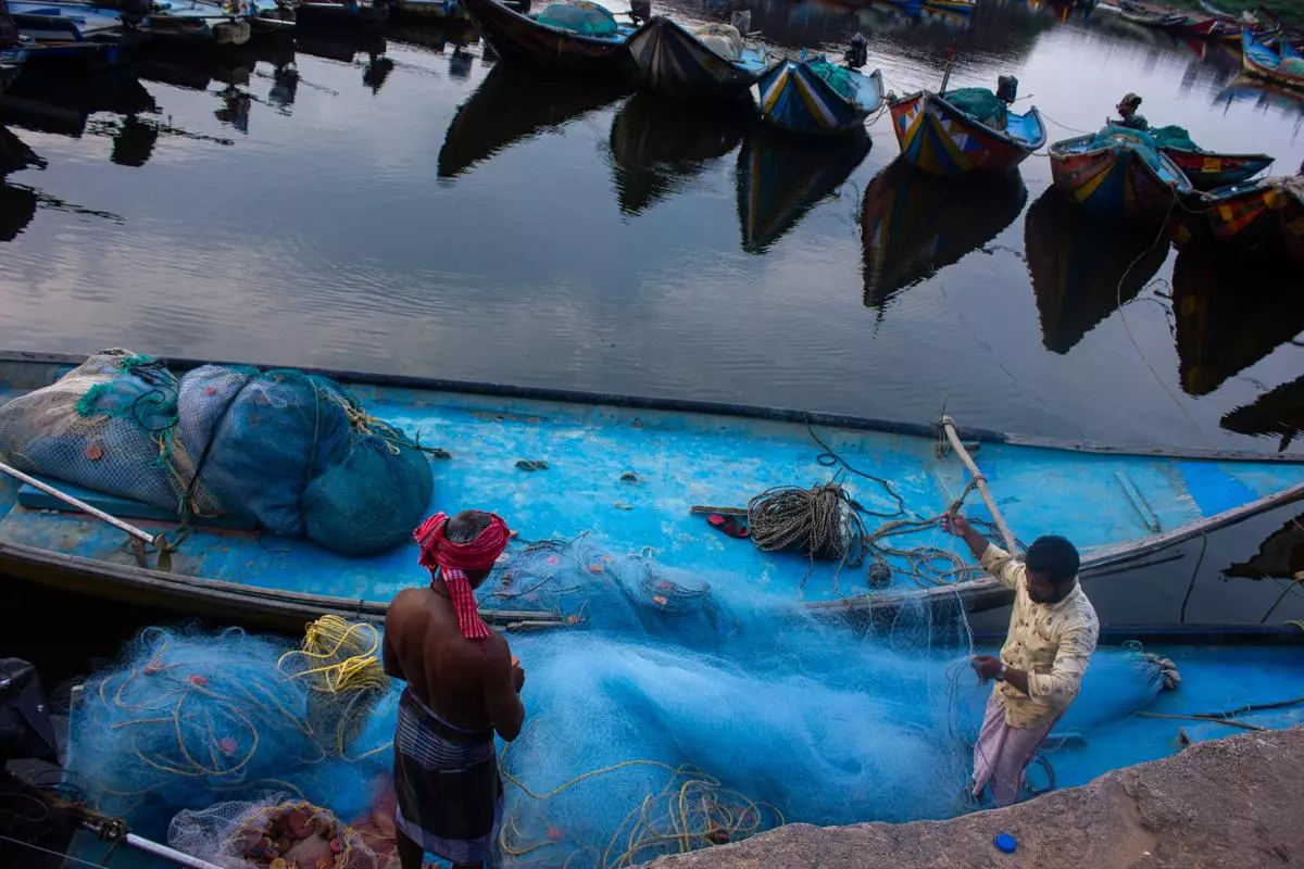 Fishermen fixing and loading their nets onto boats as they head out to catch fish.