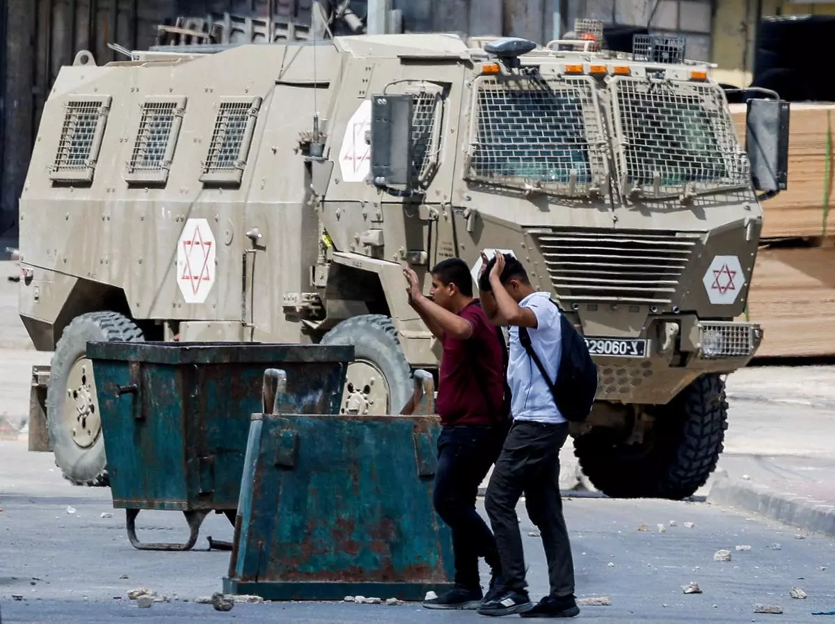 Palestinians raise their hands as they walk past Israeli forces during an Israeli raid in Qabatiya near Jenin, in the Israeli-occupied West Bank on September 19. 