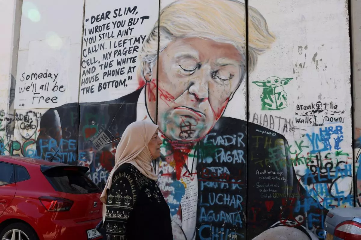 A Palestinian woman walks past a mural depicting President-elect Donald Trump on Israel’s controversial separation wall in Bethlehem in the occupied West Bank on November 5, 2024.