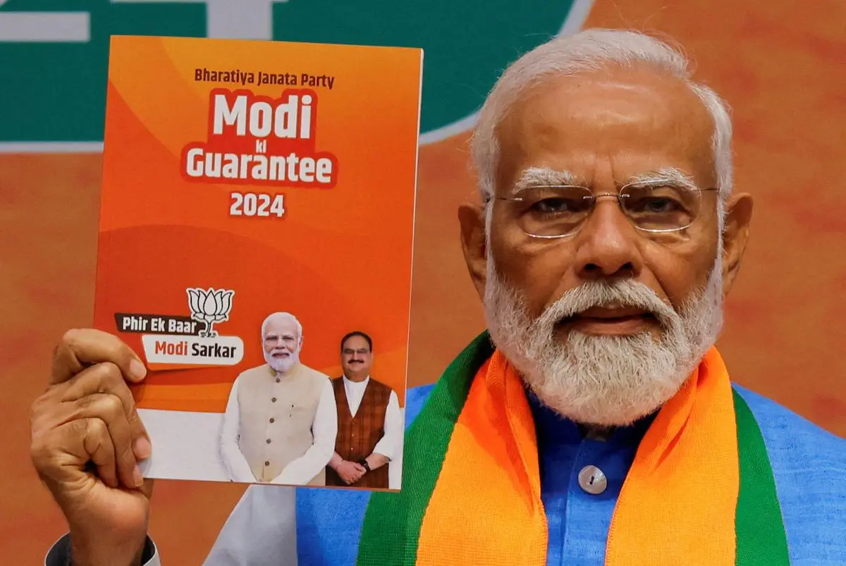 Prime Minister Narendra Modi displays a copy of the Bharatiya Janata Party’s (BJP) election manifesto for the general election, in New Delhi on April 14, 2024.