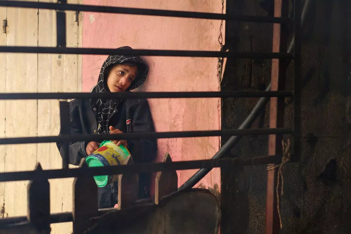 A Palestinian child waits to receive food cooked by a charity kitchen, amid shortages in food supplies, as the war between Israel and Hamas continues, in Rafah in the southern Gaza Strip on December 14, 2023.