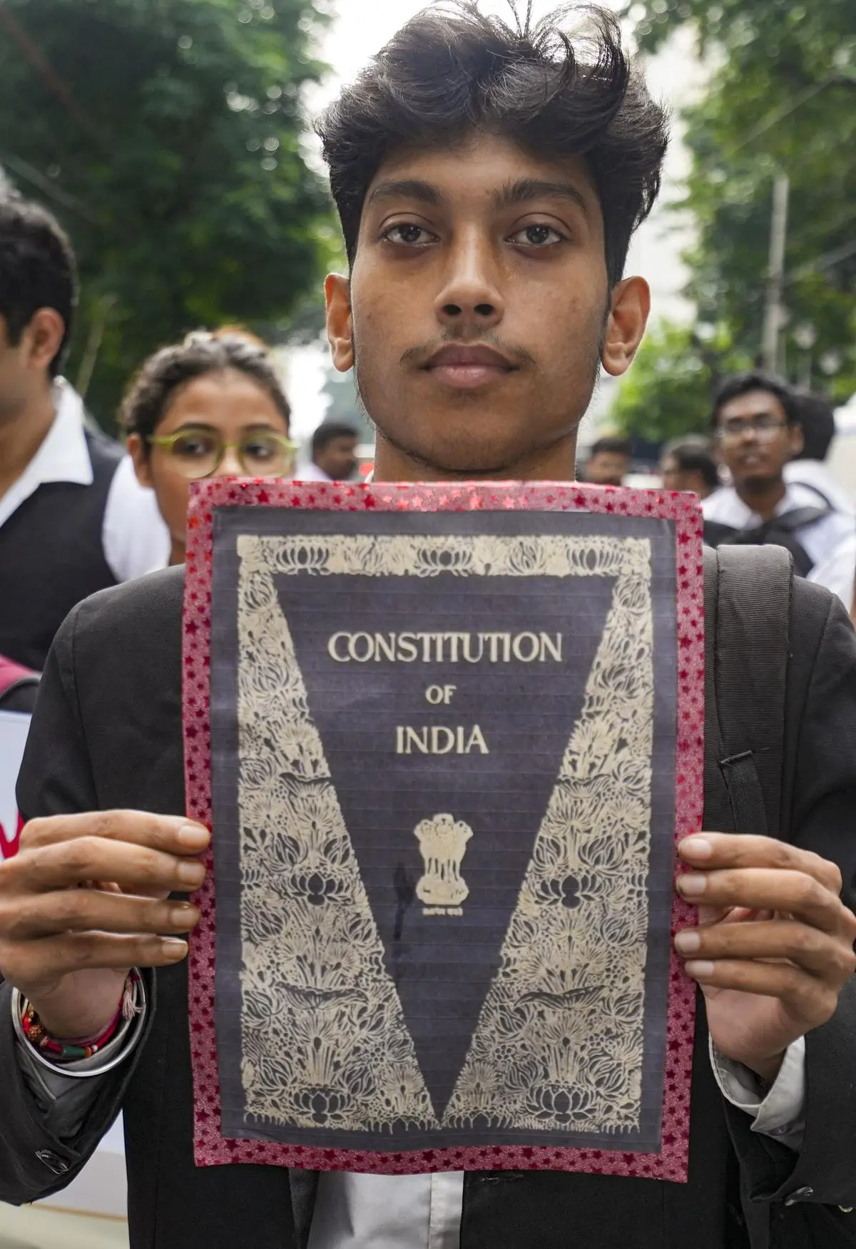 A law student holds a poster resembling the cover of the Constitution of India during a protest march in Kolkata on August 24. A law student holds a poster resembling the cover of the Constitution of India during a protest march in Kolkata on August 24.