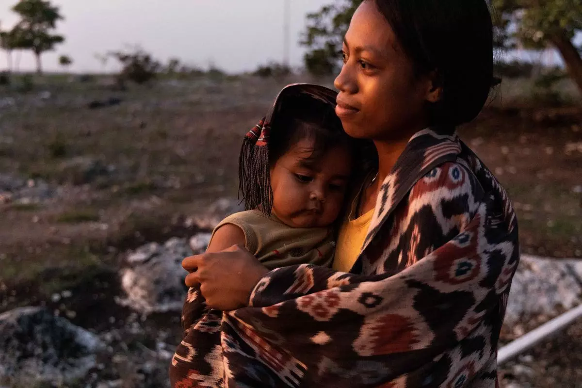 Asti, one of the children who helps in weaving, holding a younger child, Fani. The children are dressed in traditional textiles. When she is not helping to weave, Asti tends to younger children whose parents are engaged in weaving. Sumbanese culture is all about interconnectedness and inter-reliance between people. 