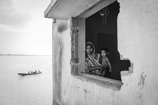A mother and her child stare at the destruction caused by the river.