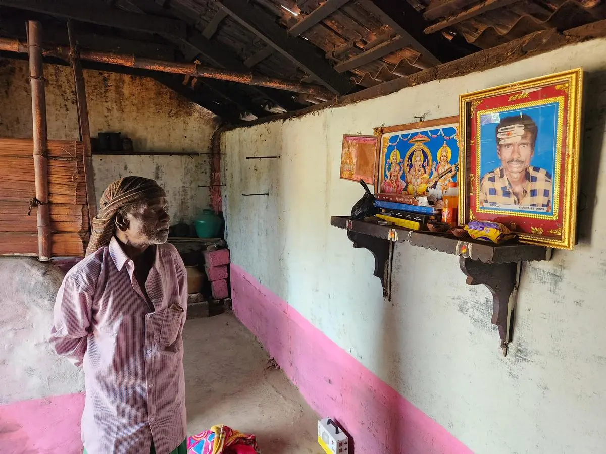 Madaiah looks at a picture of his bereaved son, Basavaiah, in Adina Kanive village. 