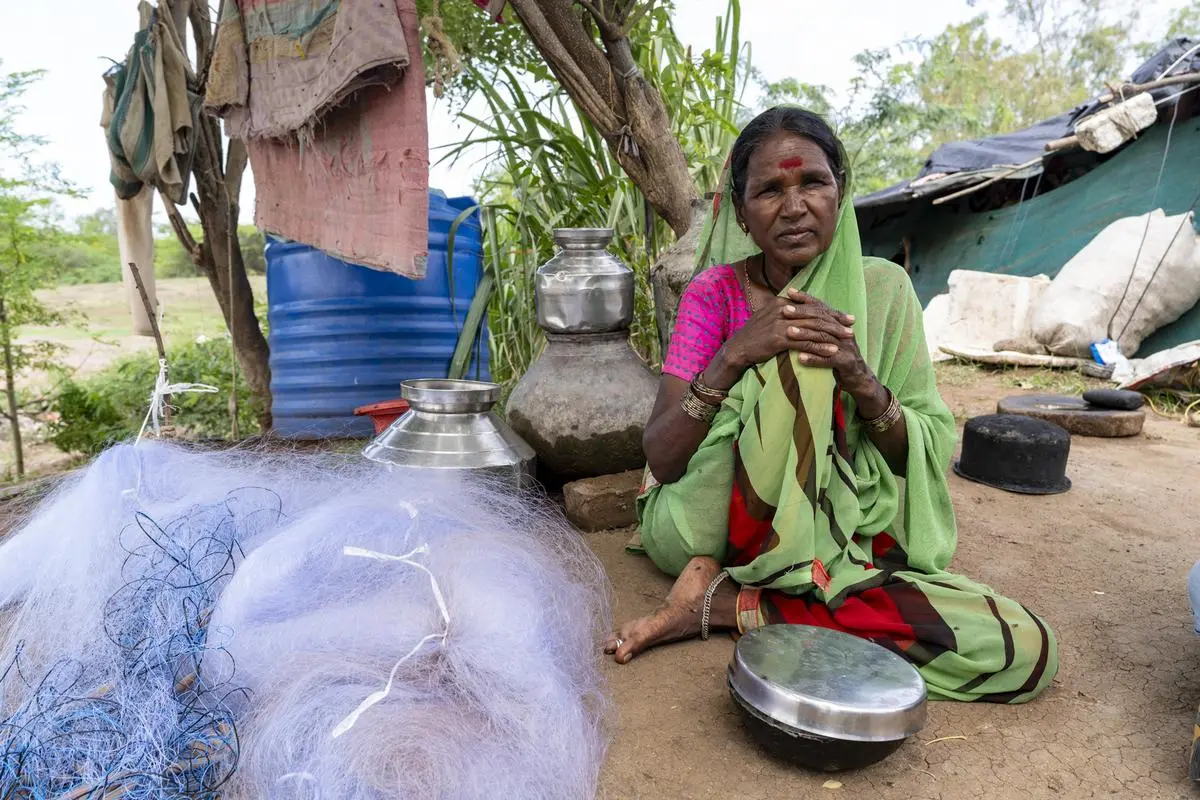 Kusumtai Kete, sitting beside her fishing net outside her makeshift house in one of the settlements in Paithan.